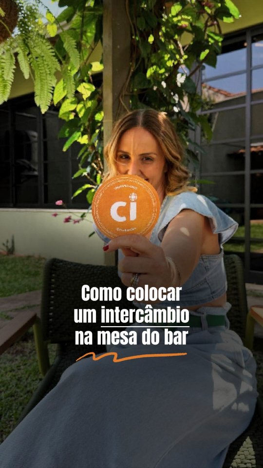 Mulher em um bar segurando uma bolacha de chope da CI Intercâmbio